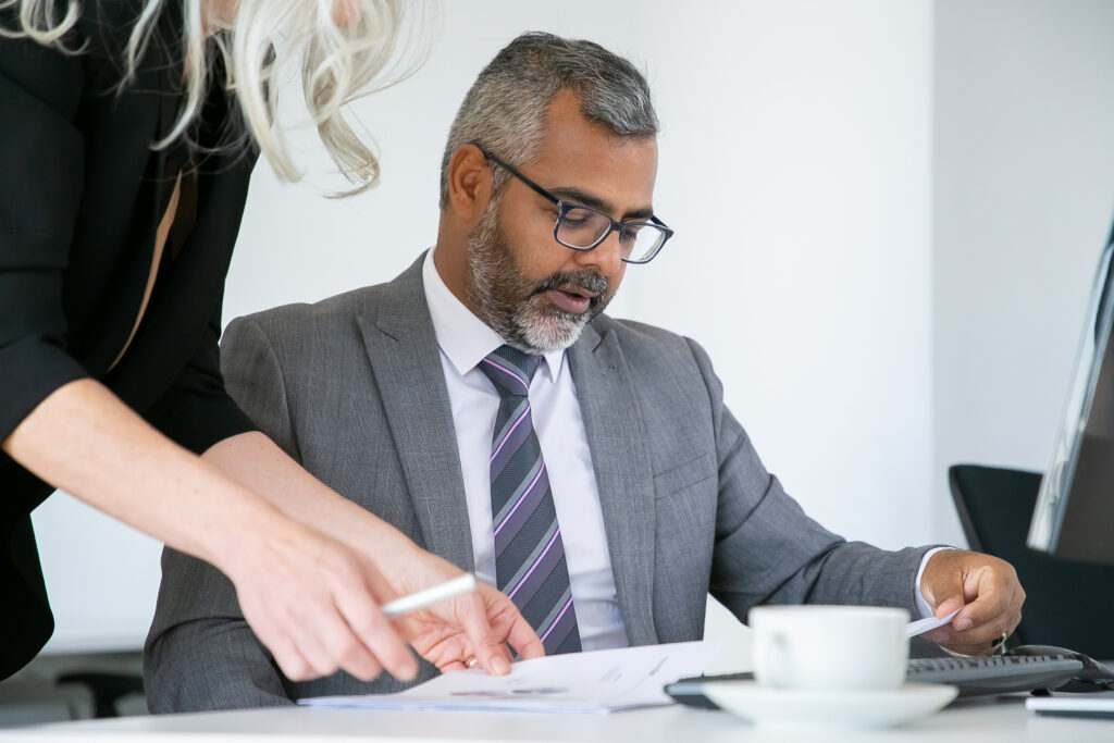 Two business partners carefully reviewing and pointing to a printed equity financing agreement at a desk.