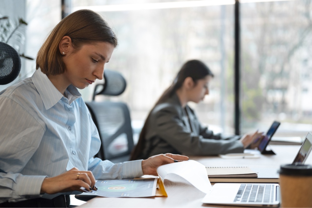 Woman looking through data while working on a laptop.