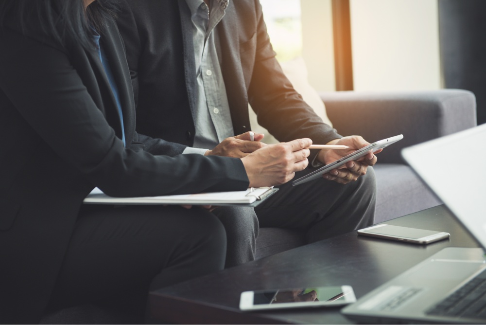 Two business professionals reviewing information on a tablet during a meeting.