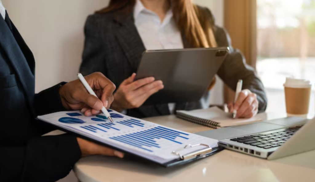 Close-up of business people reviewing bar charts on a clipboard, illustrating R&D financial planning and funding.