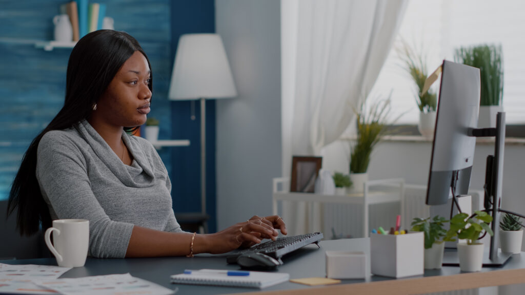 A businesswoman reviewing data on her desktop computer monitor, reflecting the challenge of tracking inflated burn rates.