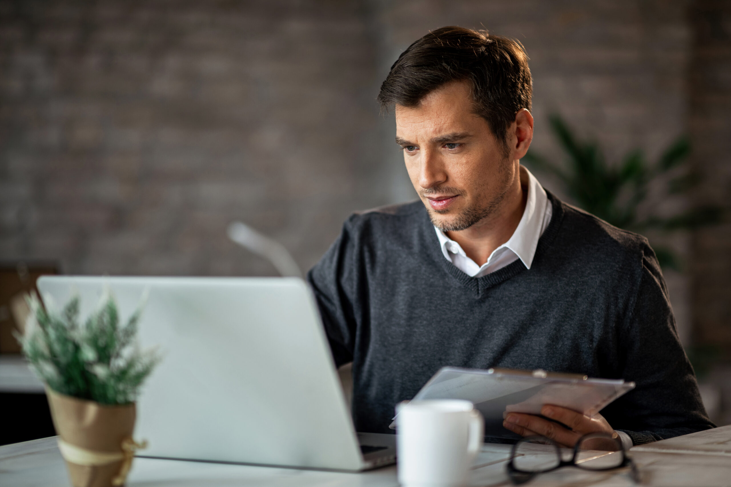 A man reviewing documents and a laptop, reflecting the focus needed to turn R&D into commercial results.