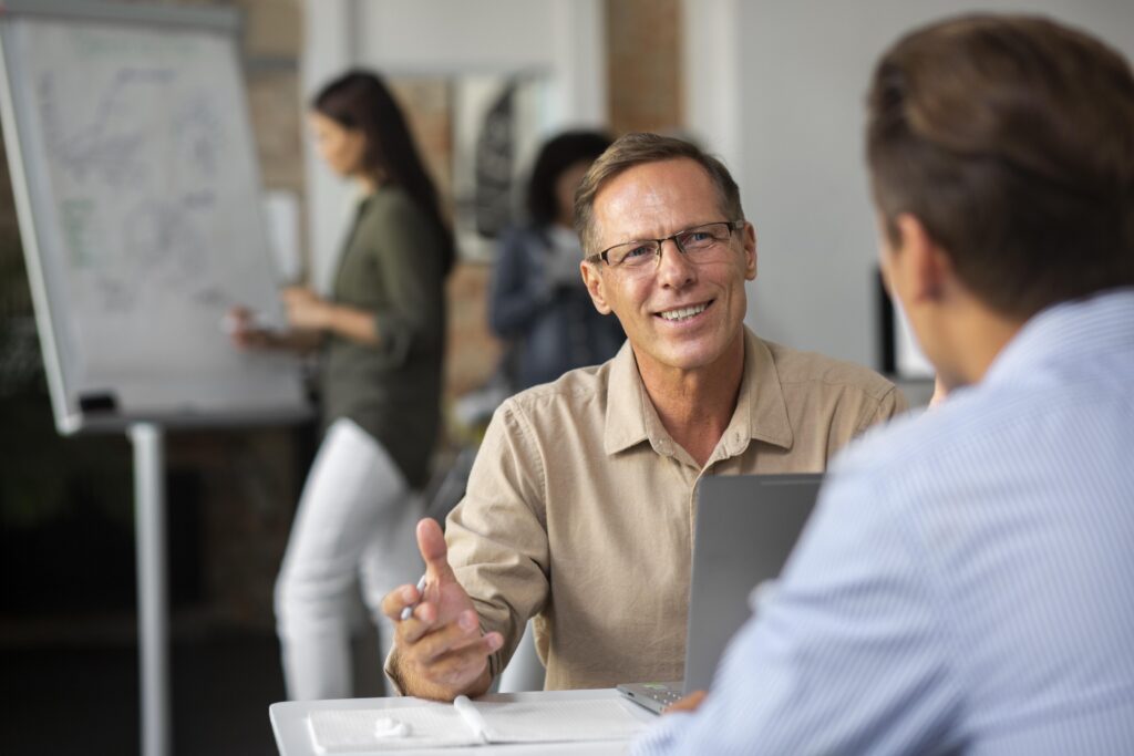 Financial advisor smiling while discussing R&D funding changes with a client in an office setting.