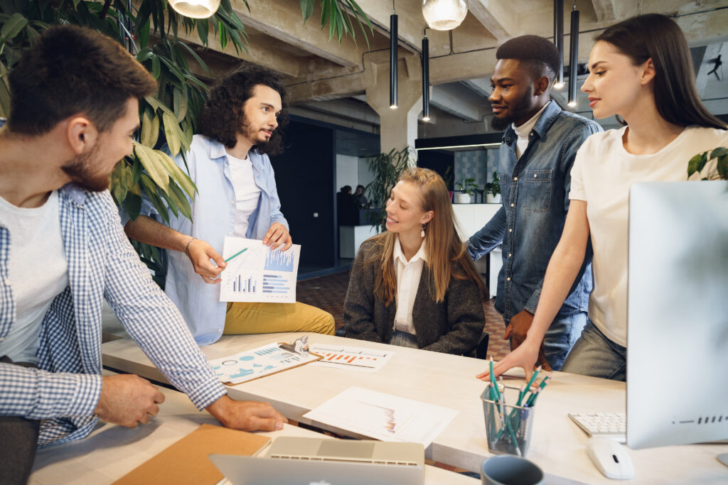 A diverse team discussing charts around a desk, representing strategic planning to make the R&D Tax Incentive work harder.