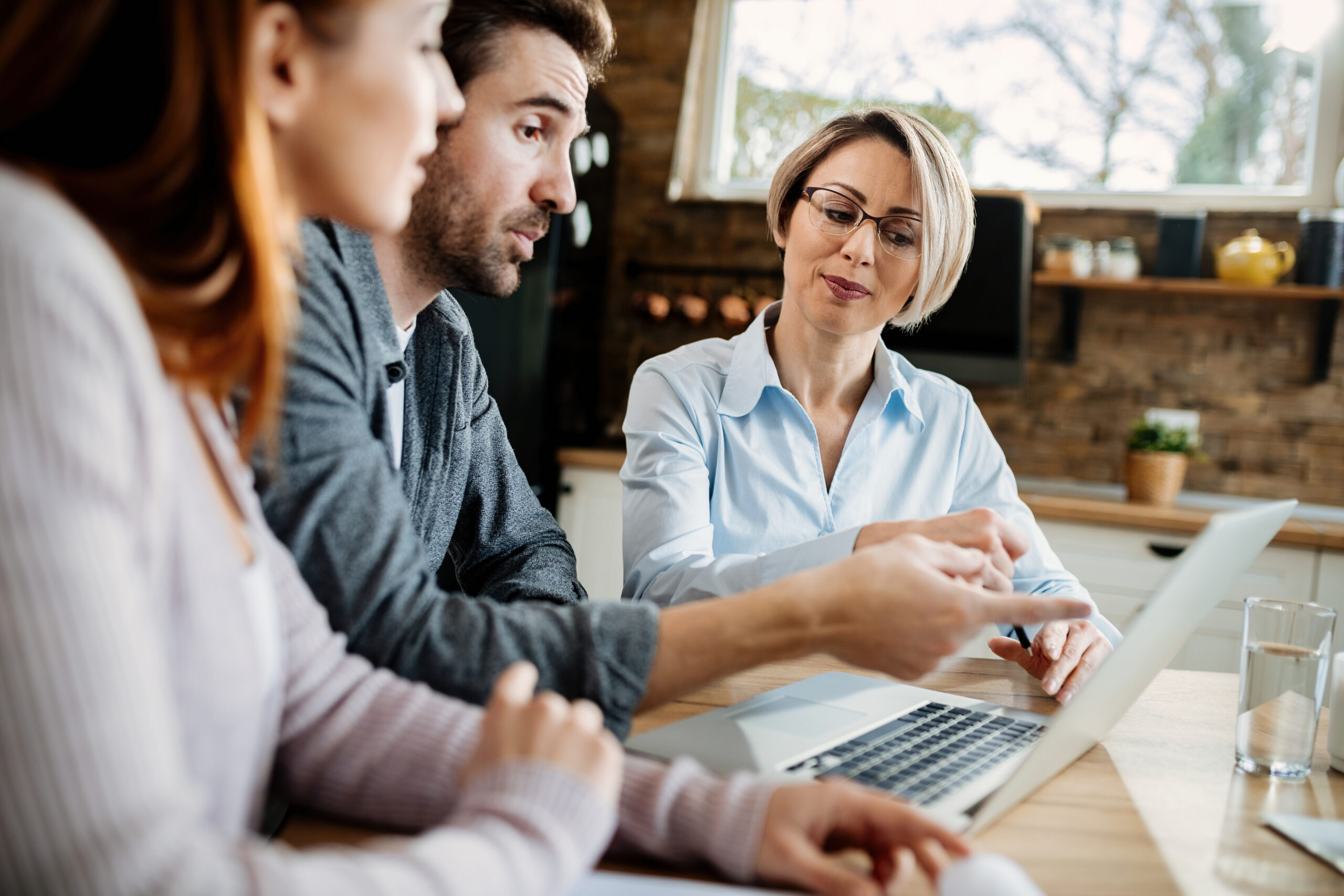 A female tax advisor points to a laptop screen, explaining the Australian R&D tax offset to two business owners.